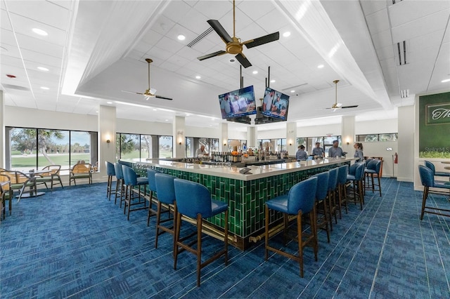 bar with ceiling fan and dark colored carpet