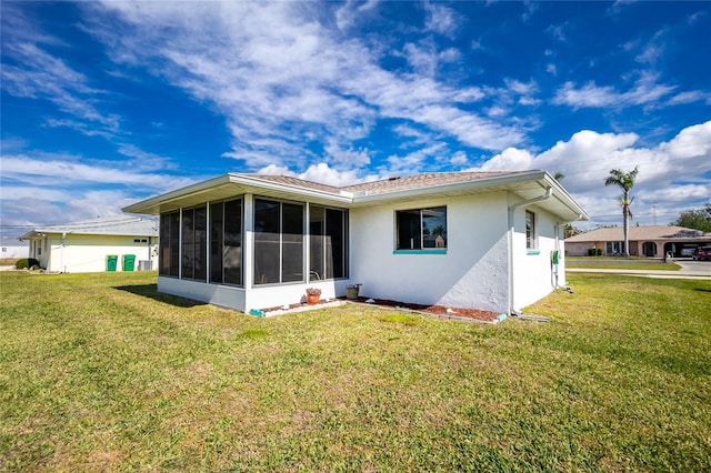 back of property featuring a lawn and a sunroom