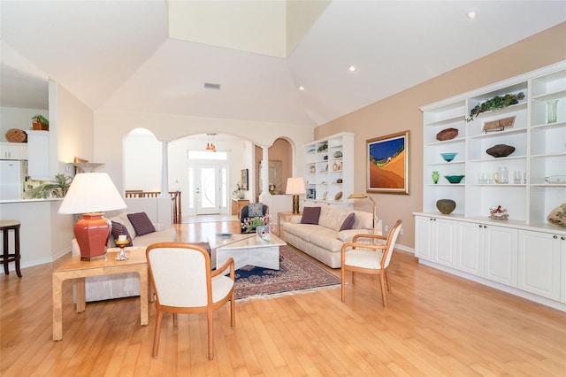 living room with vaulted ceiling, built in shelves, light hardwood / wood-style floors, and ornate columns