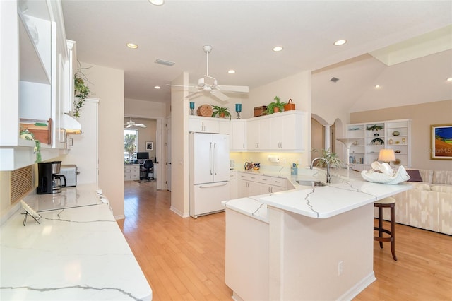 kitchen featuring sink, a breakfast bar, white cabinetry, white refrigerator, and kitchen peninsula