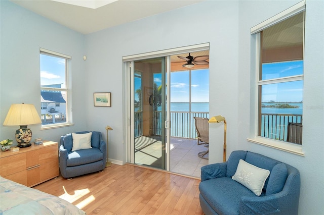 bedroom featuring a water view, access to exterior, light hardwood / wood-style floors, and multiple windows