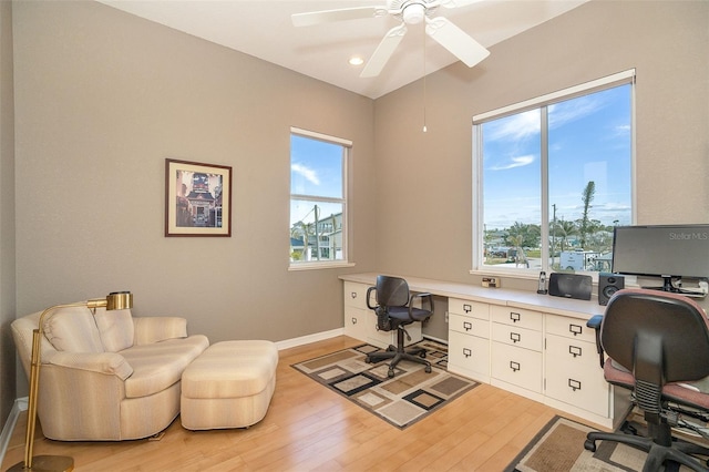 home office with built in desk, ceiling fan, and light wood-type flooring