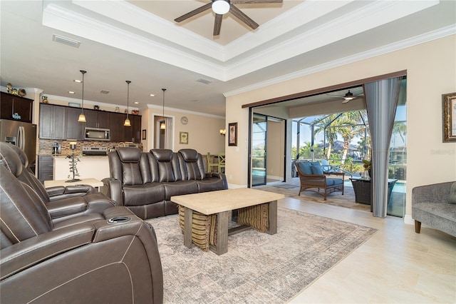 living room with ceiling fan, ornamental molding, and a tray ceiling