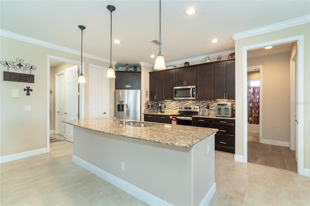 kitchen with dark brown cabinetry, sink, an island with sink, stainless steel appliances, and light stone countertops