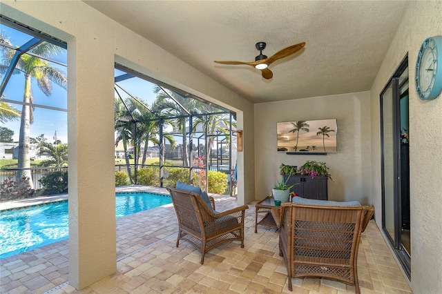 view of pool featuring an outdoor living space, a patio, ceiling fan, and glass enclosure