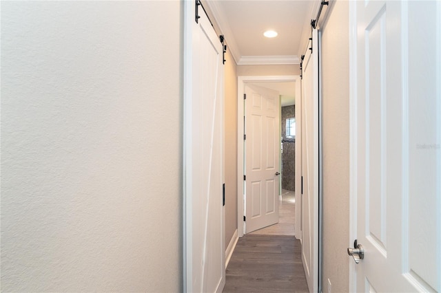 hall with crown molding, wood-type flooring, and a barn door