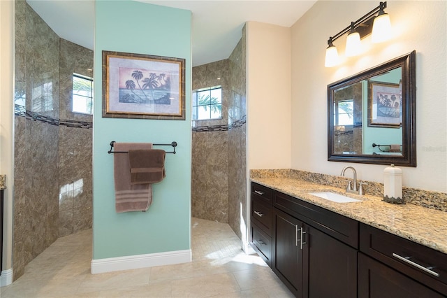 bathroom with tiled shower, vanity, and tile patterned floors