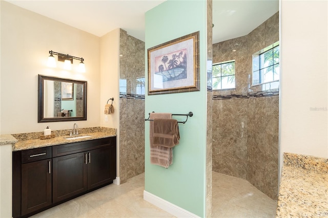 bathroom with tile patterned flooring, vanity, and a tile shower