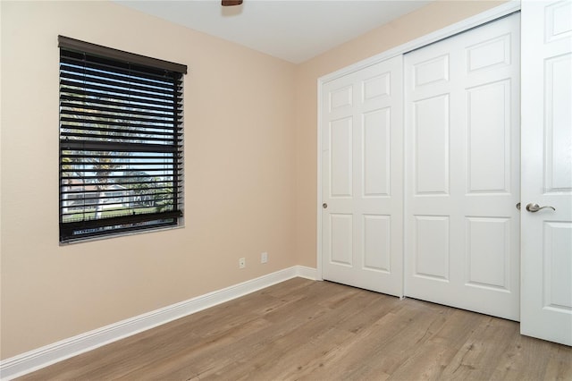 unfurnished bedroom with light wood-type flooring and a closet