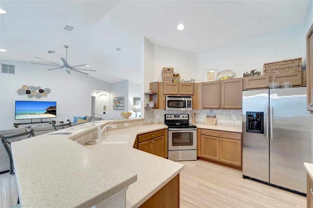 kitchen featuring lofted ceiling, sink, appliances with stainless steel finishes, tasteful backsplash, and kitchen peninsula