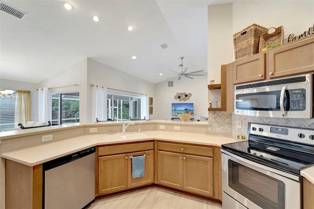 kitchen with lofted ceiling, sink, stainless steel appliances, decorative backsplash, and kitchen peninsula