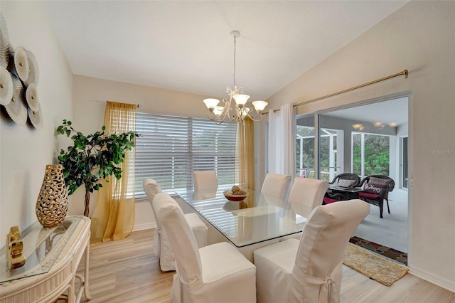 dining space with vaulted ceiling, plenty of natural light, light hardwood / wood-style floors, and a notable chandelier