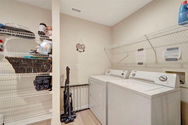 clothes washing area featuring washer and dryer and light hardwood / wood-style flooring