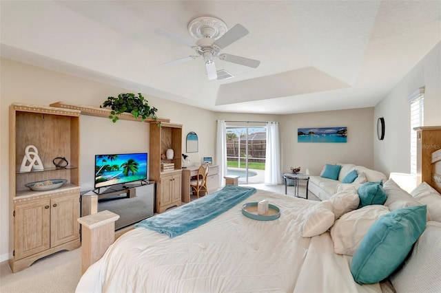 bedroom featuring light carpet, access to exterior, a raised ceiling, and ceiling fan