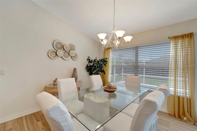 dining area with vaulted ceiling, a wealth of natural light, light hardwood / wood-style floors, and a notable chandelier