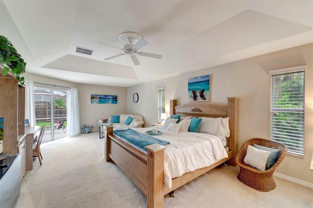 bedroom featuring a raised ceiling, light colored carpet, access to exterior, and ceiling fan