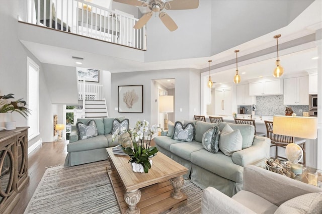 living room featuring a towering ceiling, ceiling fan, and dark wood-type flooring