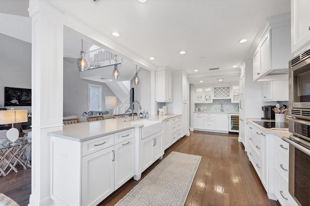 kitchen featuring tasteful backsplash, white cabinets, decorative light fixtures, sink, and wine cooler