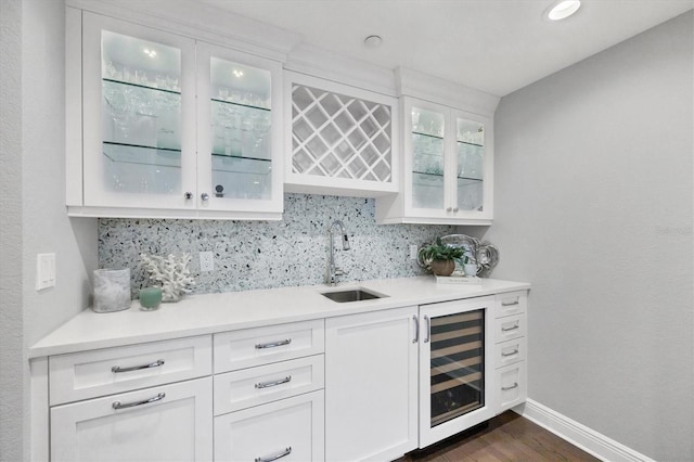 bar with white cabinets, beverage cooler, dark wood-type flooring, sink, and backsplash