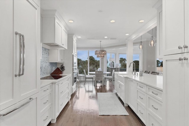 kitchen featuring pendant lighting, backsplash, white cabinetry, dark wood-type flooring, and stainless steel appliances