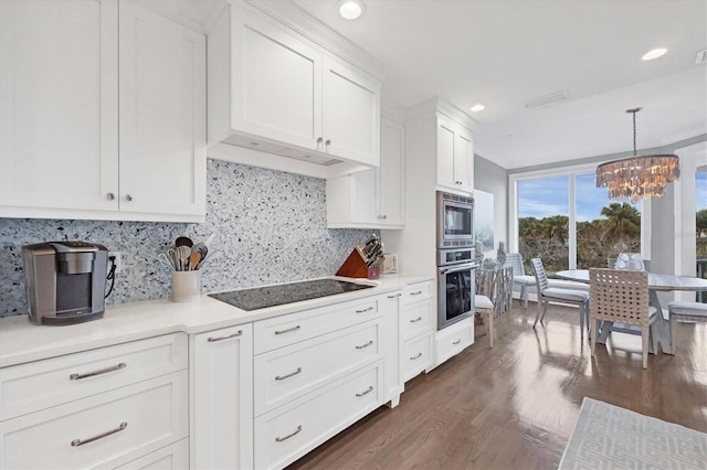 kitchen with hanging light fixtures, backsplash, dark wood-type flooring, white cabinetry, and stainless steel appliances