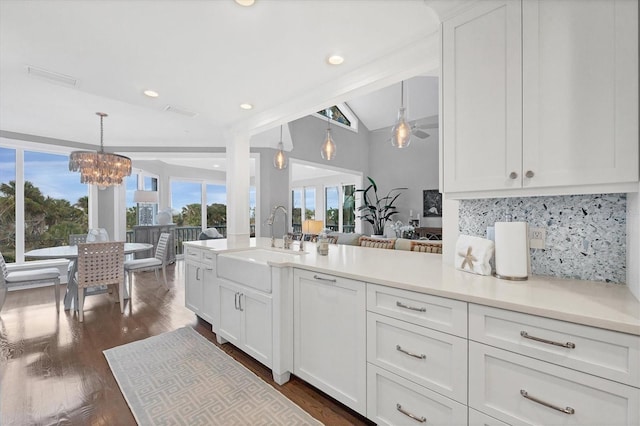 kitchen featuring lofted ceiling, decorative light fixtures, white cabinetry, tasteful backsplash, and sink