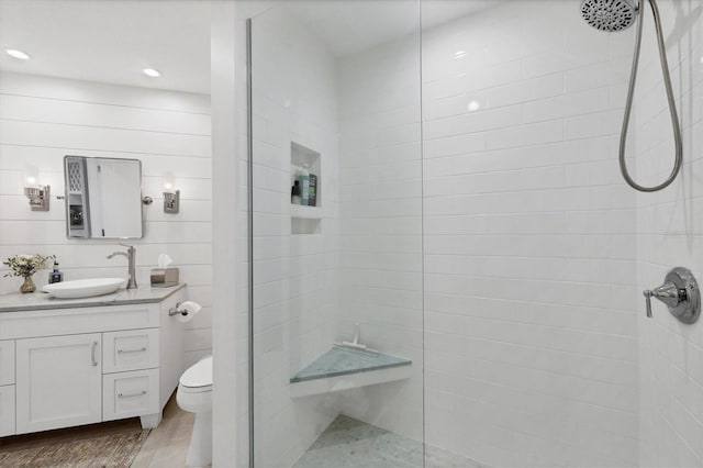 bathroom featuring a tile shower, toilet, and vanity