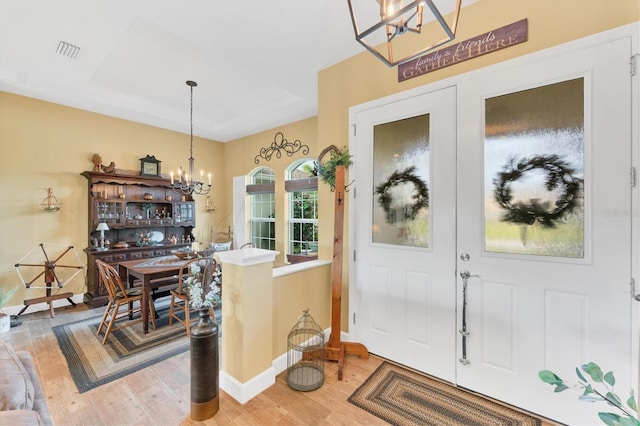 interior space with french doors, wood-type flooring, and a chandelier