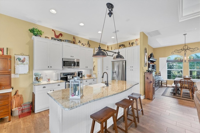 kitchen with white cabinetry, sink, hanging light fixtures, and appliances with stainless steel finishes