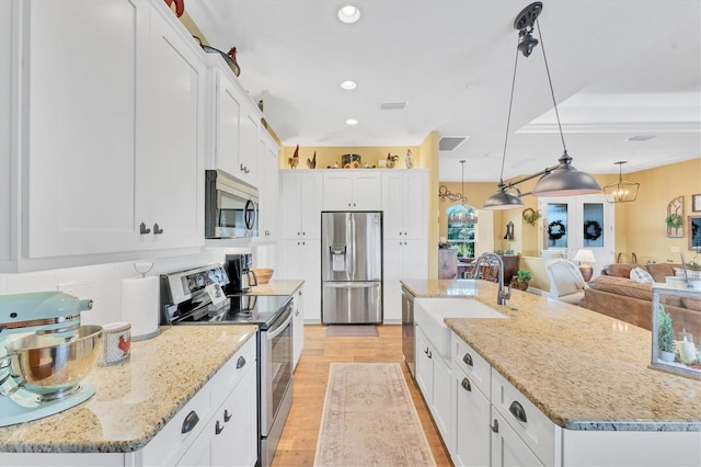 kitchen featuring white cabinetry, stainless steel appliances, a kitchen island with sink, and hanging light fixtures