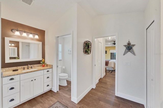 bathroom with vanity, hardwood / wood-style floors, vaulted ceiling, and toilet