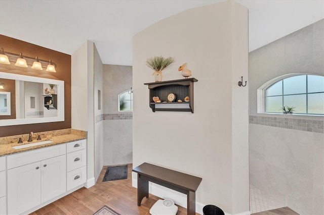 bathroom featuring hardwood / wood-style flooring, vanity, and tiled shower