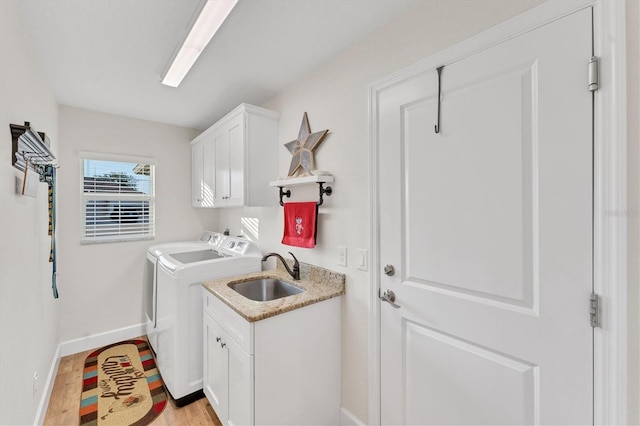 washroom featuring cabinets, separate washer and dryer, sink, and light wood-type flooring