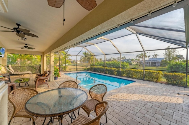 view of swimming pool with a patio area, ceiling fan, and glass enclosure