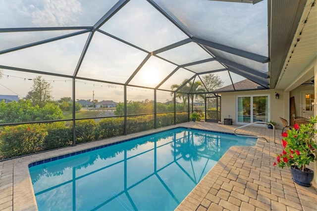 pool at dusk featuring a patio area and glass enclosure