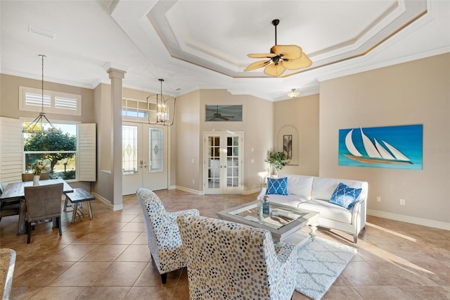 tiled living room with decorative columns, ornamental molding, ceiling fan, a tray ceiling, and french doors