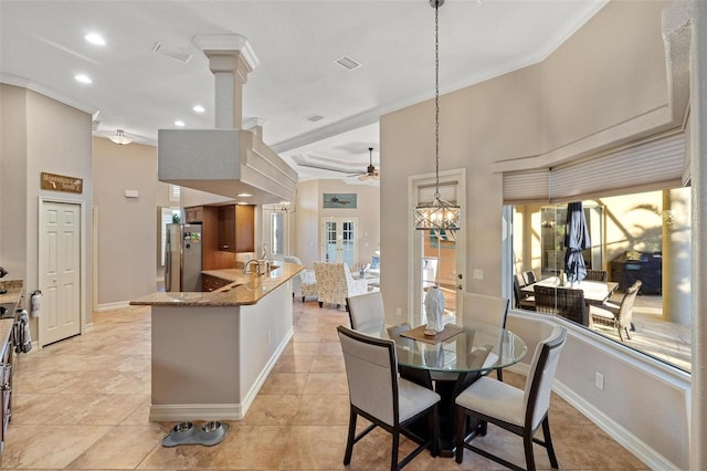 tiled dining room featuring ornate columns, ornamental molding, sink, and ceiling fan with notable chandelier