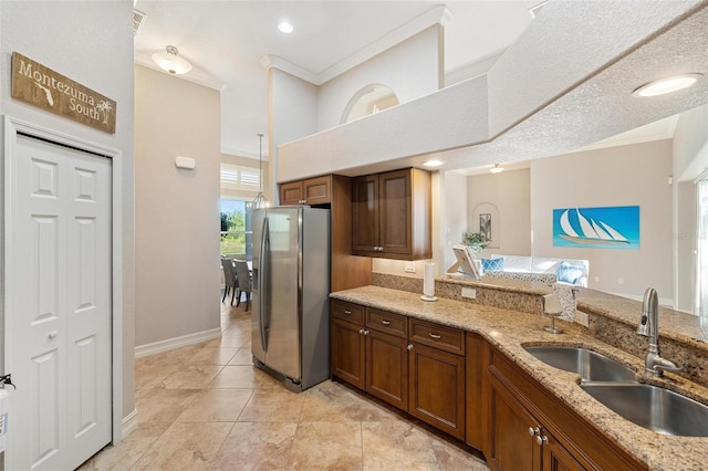 kitchen featuring stainless steel fridge with ice dispenser, sink, light stone counters, and ornamental molding