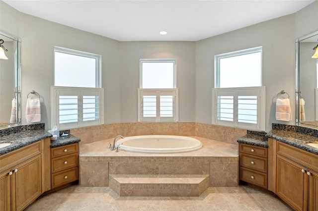 bathroom featuring a healthy amount of sunlight, tile patterned flooring, vanity, and tiled tub