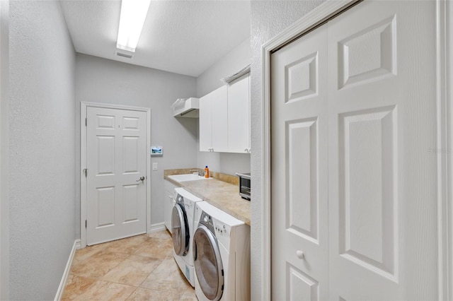 laundry room featuring washer and dryer, a textured ceiling, cabinet space, light tile patterned flooring, and baseboards