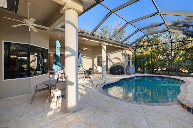 outdoor pool featuring glass enclosure, a patio, and a ceiling fan