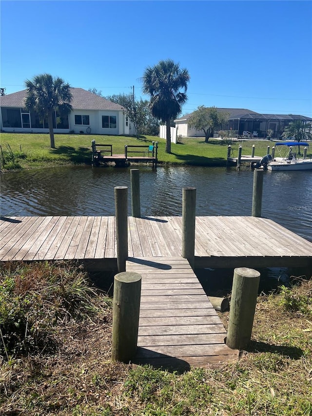 view of dock with a yard and a water view