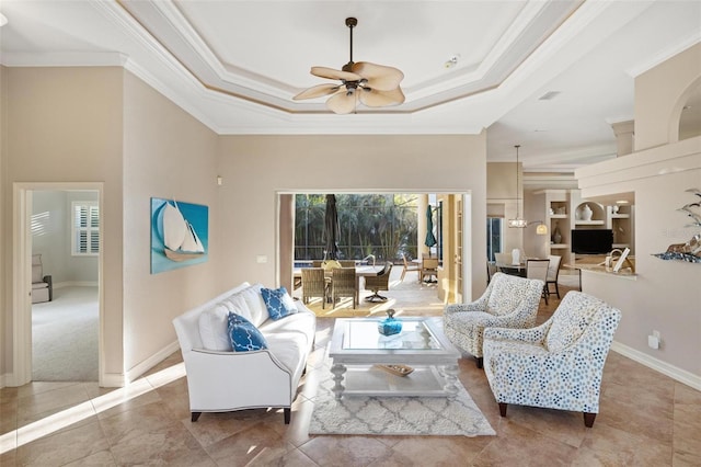 living room featuring a tray ceiling, baseboards, ceiling fan, and crown molding