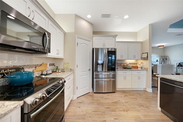 kitchen featuring appliances with stainless steel finishes, light stone countertops, light wood-type flooring, and white cabinets