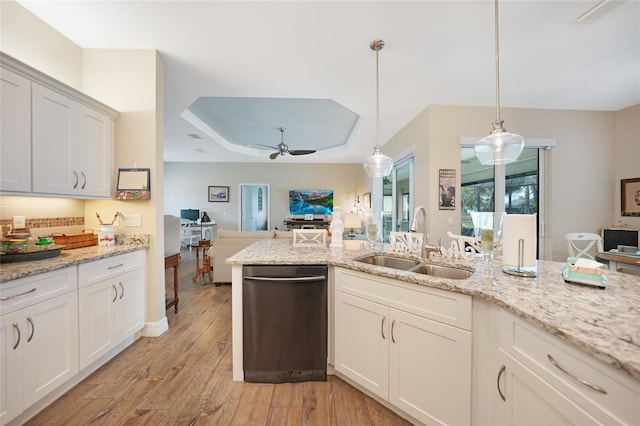 kitchen featuring white cabinetry, sink, hanging light fixtures, light stone counters, and light wood-type flooring