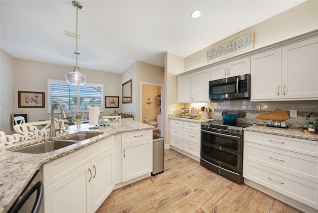 kitchen featuring decorative light fixtures, sink, stainless steel appliances, light stone countertops, and light hardwood / wood-style flooring