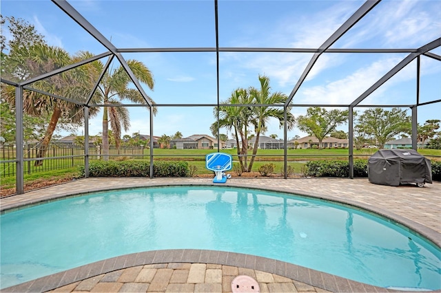 view of swimming pool featuring a grill, a patio area, and glass enclosure