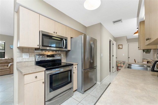 kitchen with sink, decorative backsplash, light tile patterned floors, stainless steel appliances, and light brown cabinets