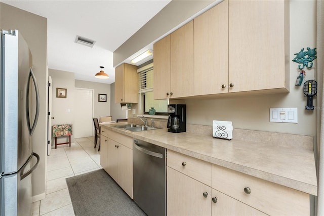 kitchen featuring light brown cabinetry, sink, decorative light fixtures, light tile patterned floors, and stainless steel appliances