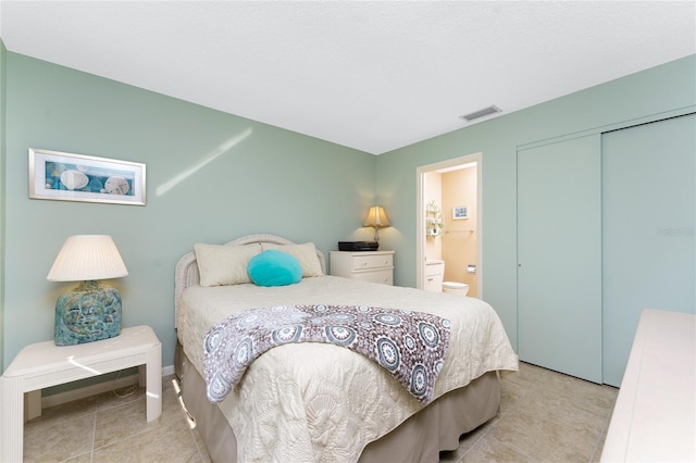 tiled bedroom with a closet and ensuite bathroom